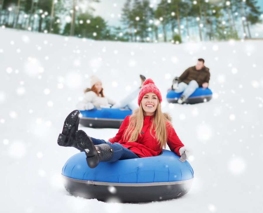 49525334+-+winter%2C+leisure%2C+sport%2C+friendship+and+people+concept+-+group+of+happy+friends+sliding+down+on+snow+tubes