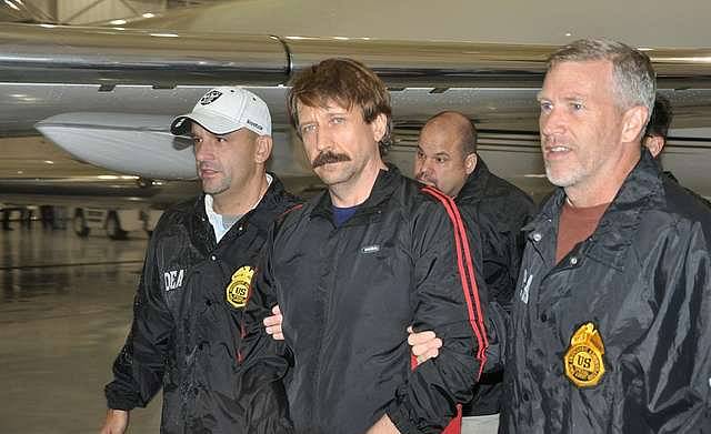 Viktor Bout, a Russian arms dealer nicknamed the “Merchant of Death”, is escorted into the United States as a prisoner after being detained in Thailand two years prior following an international sting operation.